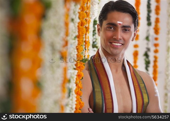Close-up of smiling groom standing near garland