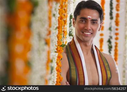 Close-up of smiling groom standing near garland