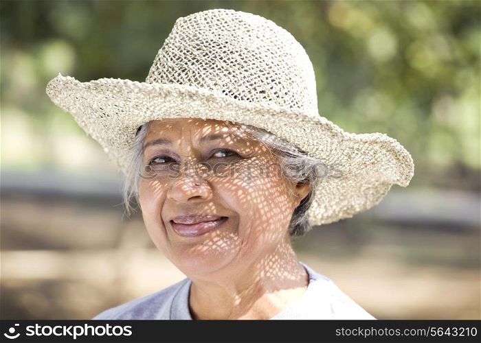 Close-up of smiling mature woman wearing hat at park