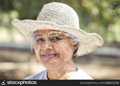 Close-up of smiling mature woman wearing hat at park