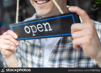 Close Up Of Smiling Small Business Owner Turning Around Open Sign On Shop Or Store Window Or Door