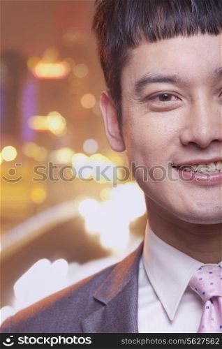 Close-up of smiling young business man, city lights background