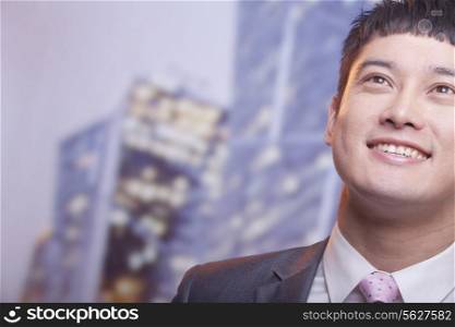 Close-up of smiling young business man looking up