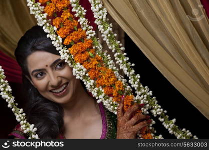 Close-up of smiling young Indian woman looking away with wreath