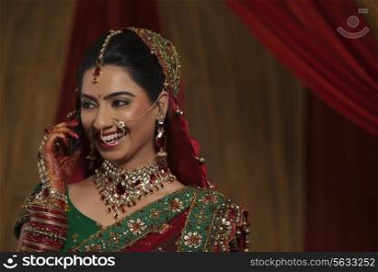 Close up of smiling young Indian woman talking on cell phone while looking away