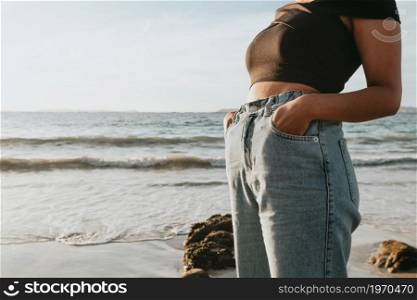 Close up of some mom jeans on a young woman during a sunny day at the beach with copy space