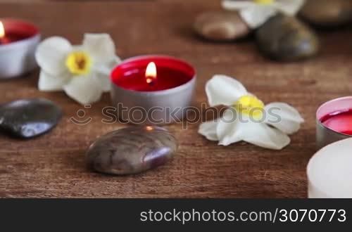 Close-up of spa still life bath salt scrub with flowers, rocks, massage oil, towel and candles
