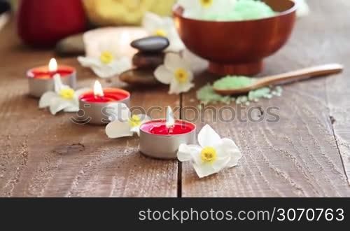 Close-up of spa still life salt scrub with flowers, rocks, towel and candles