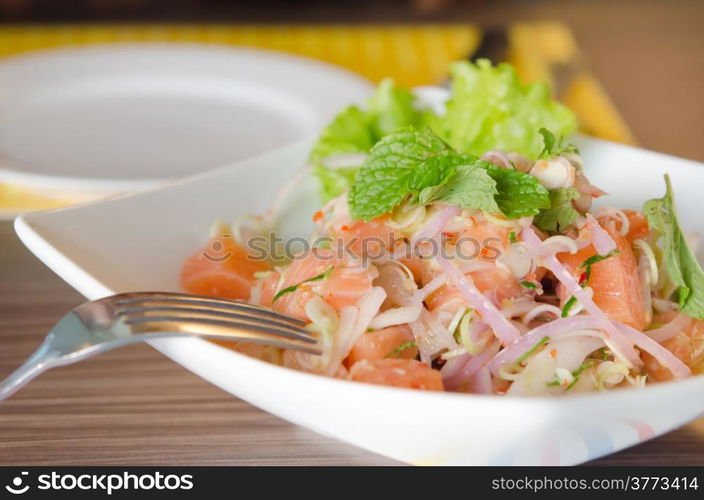 close up of spicy salmon salad with mixed vegetable with silver fork. spicy salmon salad