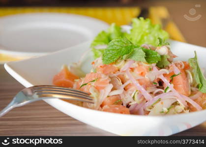 close up of spicy salmon salad with mixed vegetable with silver fork. spicy salmon salad