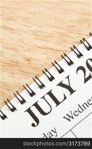 Close up of spiral bound calendar displaying month of July.