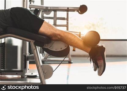 Close up of sport man stretching and lifting weight by two legs when facing down for stretching muscle at fitness gym at condominium background. Sport and People lifestyles concept.