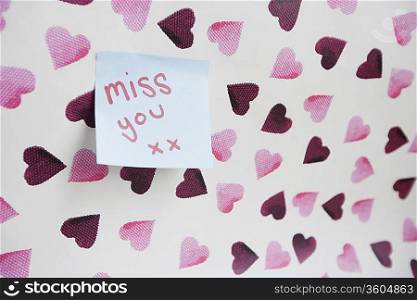 Close-up of sticky note with a message over heart shaped wall