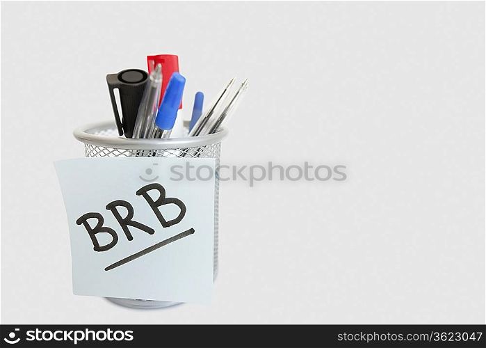 Close-up of sticky note with message on pen holder over white background