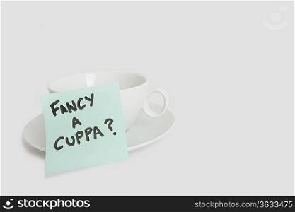 Close-up of sticky notepad stuck to empty coffee cup over white background