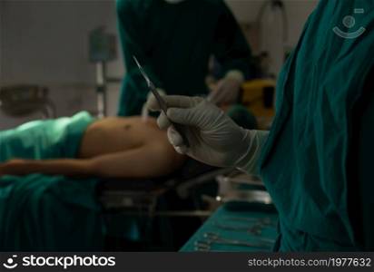Close-up of surgeon&rsquo;s hand with medical latex glove holding scalpel for operation in a hospital operating room