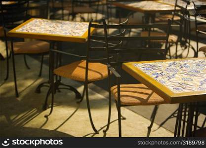 Close-up of tables and chairs at a sidewalk cafe