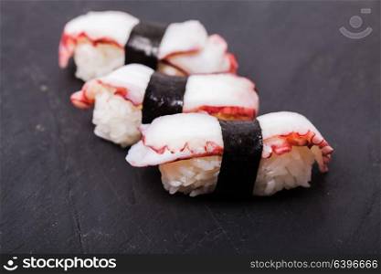Close-up of Tako nigiri sushi with cooked octopus on a black slate background. Tako nigiri sushi