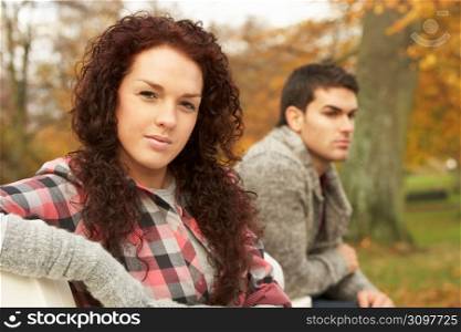 Close Up Of Teenage Couple Sitting On Bench In Autumn Park