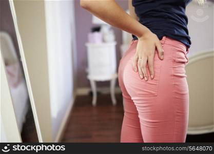 Close Up Of Teenage Girl Putting On Trousers In Bedroom