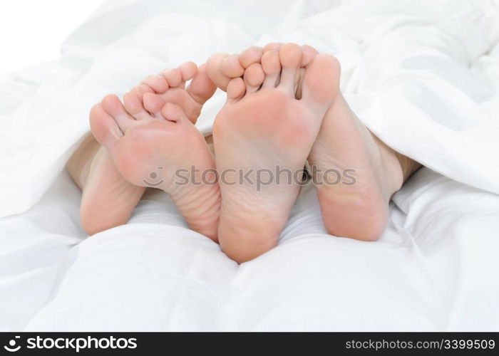 Close-up of the feet of a couple on the bed. Isolated on white background