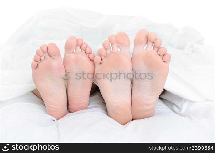 Close-up of the feet of a couple on the bed. Isolated on white background