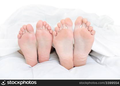 Close-up of the feet of a couple on the bed. Isolated on white background