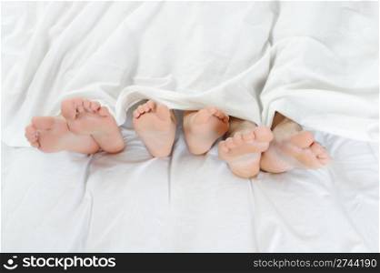 Close-up of the feet of a family on the bed
