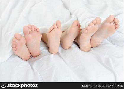 Close-up of the feet of a family on the bed. Isolated on white background