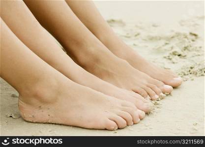 Close-up of the feet of two people on sand