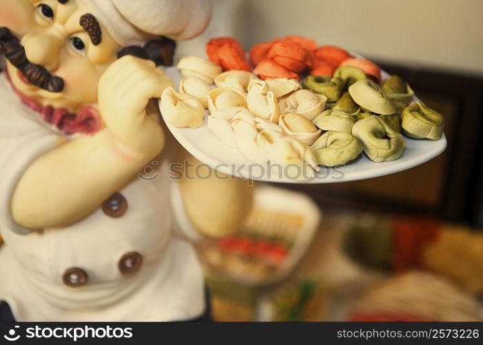 Close-up of the figurine of a chef holding dumplings in a plate
