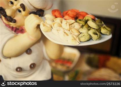Close-up of the figurine of a chef holding dumplings in a plate