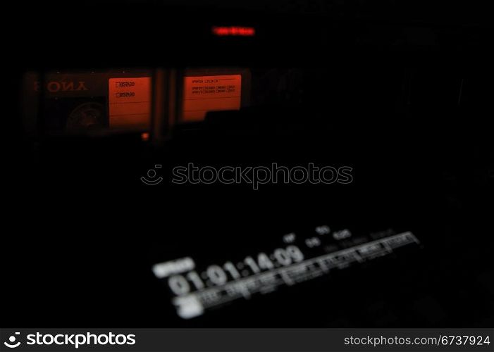 Close-up of the front panel of the professional digital betacam video recorder. Low key, shallow dof. Tape, display with timecode.