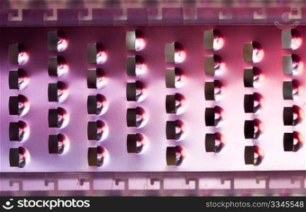 Close up of the slots in a stainless steel cheese grater lit from the side with color lights
