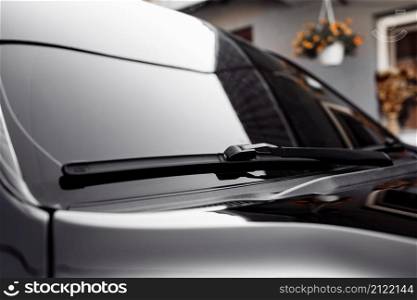 Close up of the windshield and wipers of a modern car. Automotive industry. Close up view of a pair of car wiper blades with small raindrops on window. Close up of the windshield and wipers of a modern car. Automotive industry. Close up view of a pair of car wiper blades with small raindrops on window.