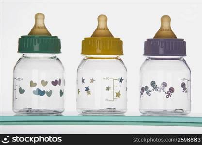 Close-up of three baby bottles on a shelf