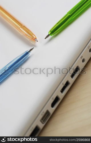 Close-up of three ballpoint pens on a laptop