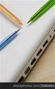 Close-up of three ballpoint pens on a laptop
