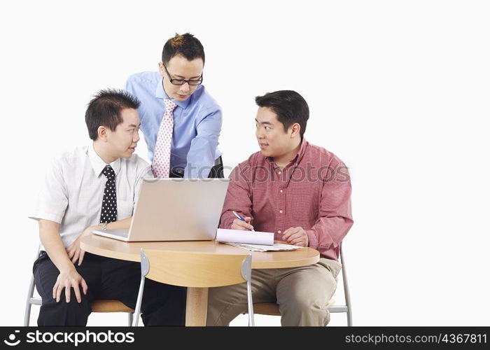 Close-up of three businessmen discussing in front of a laptop