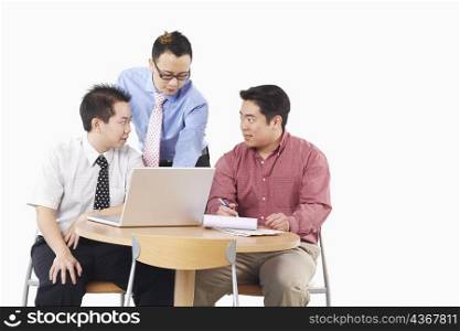 Close-up of three businessmen discussing in front of a laptop