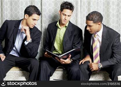 Close-up of three businessmen reading a file