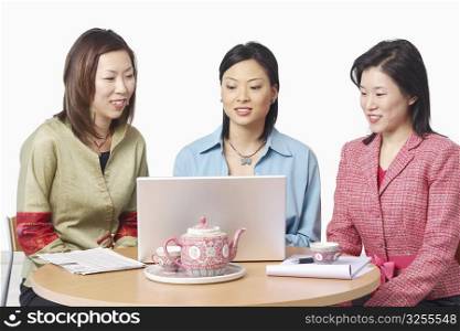 Close-up of three businesswomen in front of a laptop