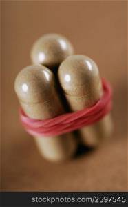 Close-up of three capsules tied with a rubber band