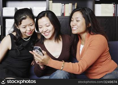 Close-up of three friends looking at a mobile phone smiling