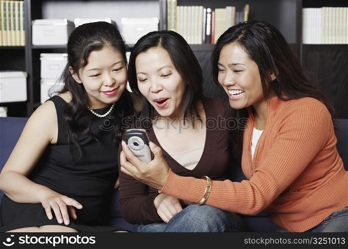 Close-up of three friends looking at a mobile phone smiling