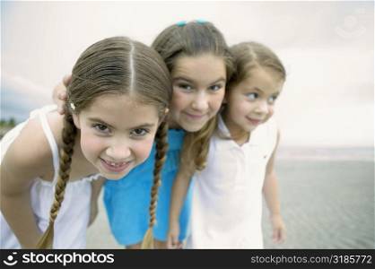 Close-up of three girls standing together on the beach