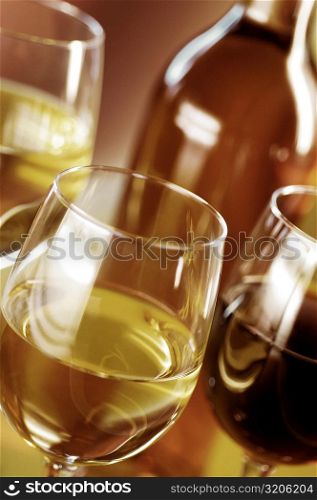Close-up of three glasses of wine with a wine bottle