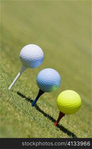 Close-up of three golf balls on three tees on a golf course