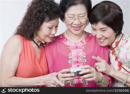 Close-up of three senior women looking at a digital camera and smiling