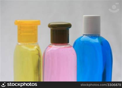 Close up of three shampoo bottles in yellow, pink and blue